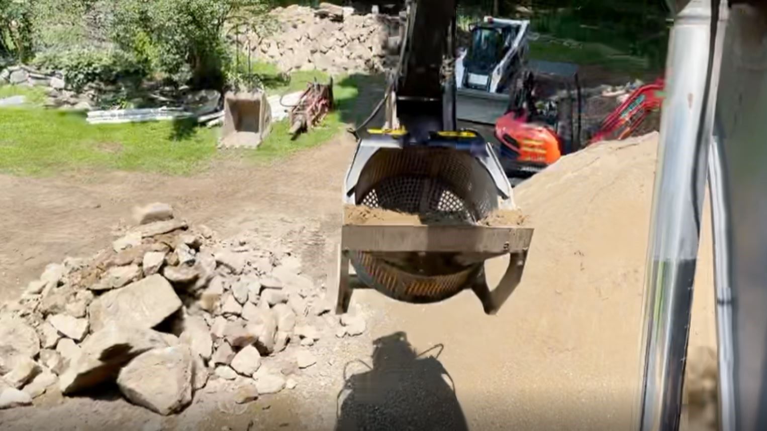 	The MB-S14 screening bucket separating rocks from the dirt and reuse the material to create concrete for the house’s footing. 