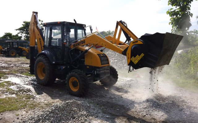 The MB stone crusher is mounted on a Manitou backhoe loader and it's crushing river bed material.