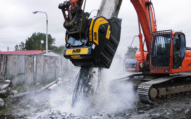 Una benna frantoio BF70.2 frantuma cemento armato e materiale inerte collegato in cantiere.