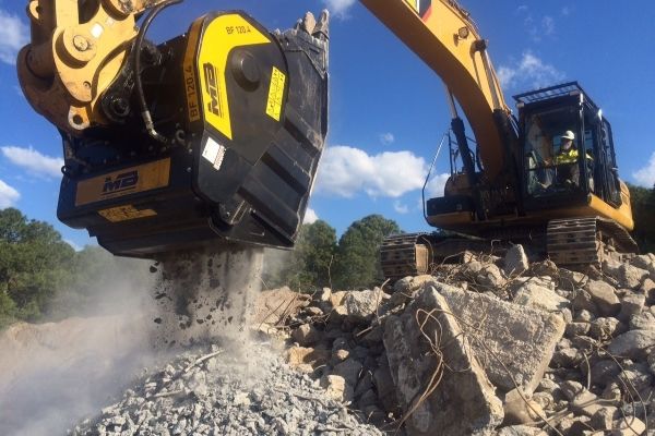 La benna frantoio BF120.4 frantuma blocchi di cemento armato su un escavatore Caterpillar La benna frantoio BF120.4 frantuma blocchi di cemento armato su un escavatore Caterpillar