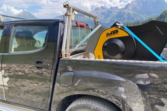 MB Crusher Backenbrecherlöffel C50 S4 montiert auf Bagger Kobelco zerkleinert Steine in den Schweizer Alpen um sie als Untergrund für Wege wiederzuverwenden