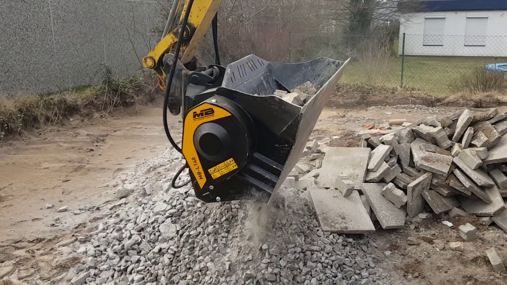 The MB-L140 crusher bucket crushing bricks on a mini-excavator to reuse as fill.